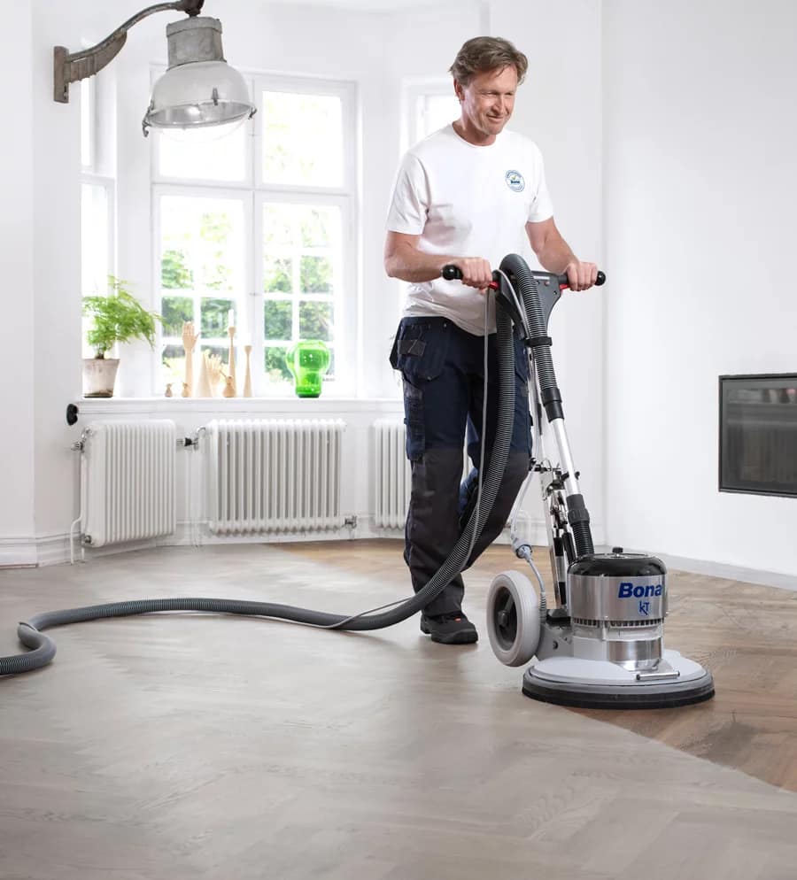 Handwerker schleift Dielenboden mit professioneller Schleifmaschine – Bodenhandwerk Harz
